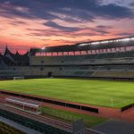 Stadion sepak bola Indonesia dengan lapangan hijau dan tribun yang bersiap untuk pertandingan liga