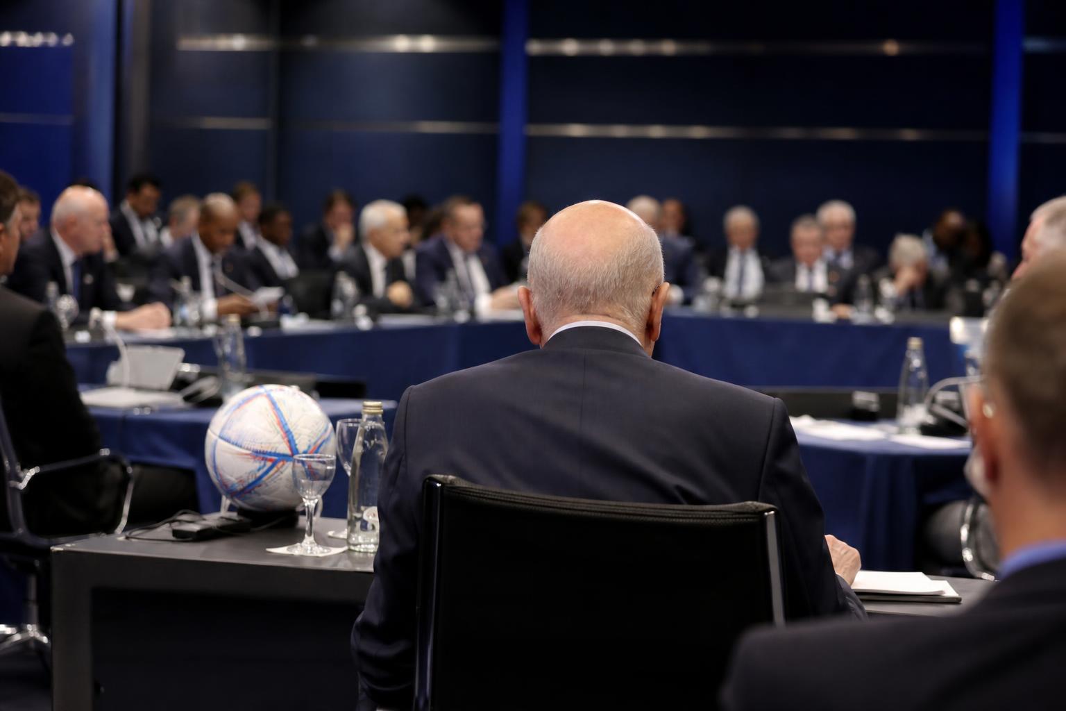 Suasana rapat tata kelola sepak bola internasional dengan para delegasi dan seorang pejabat senior di meja konferensi