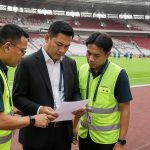 Match commissioner berdiskusi dengan staf operasional di sisi lapangan stadion sebelum pertandingan sepak bola