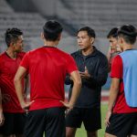 Regulasi Pemain U21 Pegadaian Championship 2026/2027 Pemain muda sepak bola berdiskusi dengan pelatih di lapangan stadion sebelum pertandingan