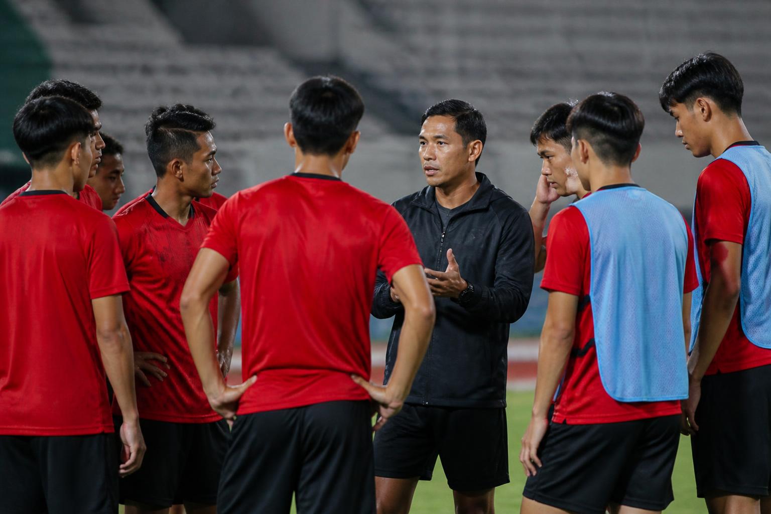 Pemain muda sepak bola berdiskusi dengan pelatih di lapangan stadion sebelum pertandingan